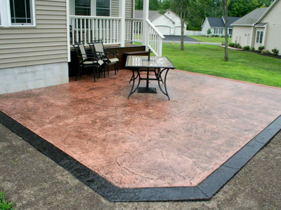 Decorative concrete patio stamped and stained and bordered with darker colored stamped concrete.